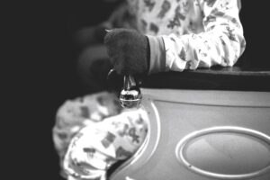 A child in pajamas sits on a chair holding a bell